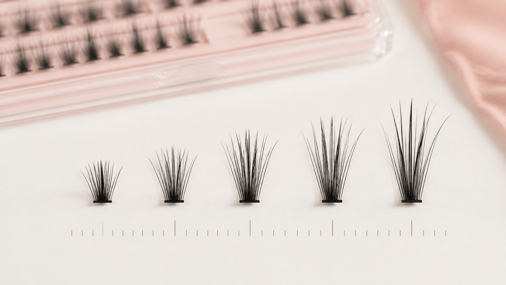 Five DIY lash clusters arranged from shortest to longest above measurement marks
